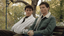 two men are sitting on a park bench with the words oxylane dna visible in the corner