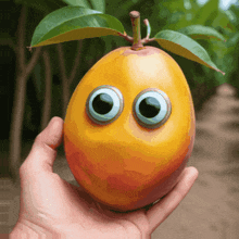 a person is holding a mango with googly eyes and green leaves