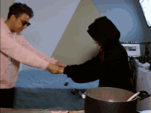 two people holding hands in front of a pot