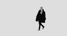 a black and white photo of a man in a black coat walking .