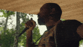 a man singing into a microphone under a canopy