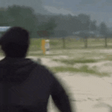 a man in a black jacket is walking across a field .