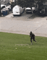 a man is running on a grassy field with a white van parked in the background