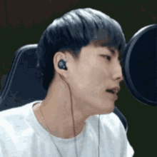 a young man wearing headphones is sitting in front of a microphone and making a funny face .