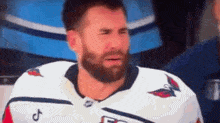 a man with a beard is crying while wearing a hockey uniform .
