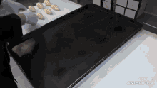 a black tray with croissants on it and the words made in animatica on the bottom
