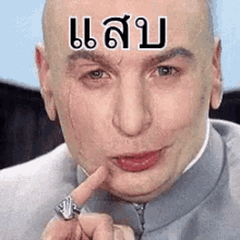 a bald man with a ring on his finger and a foreign language on his forehead .