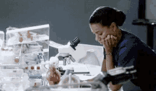 a woman is looking through a microscope in a laboratory