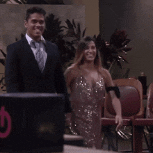 a man in a suit and tie stands next to a woman in a pink dress