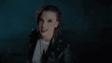 a woman wearing a black leather jacket and a white shirt looks angry