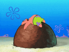 patrick star is laying on top of a large rock in the sand