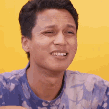 a man in a blue shirt is making a funny face with his eyes closed