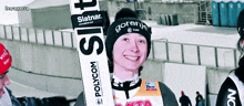 a man wearing a gorenje hat holds skis