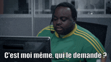 a man wearing a headset is sitting in front of a computer with the words " c'est moi meme qui le demande " above him