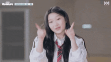 a girl in a school uniform and tie is making a heart shape with her hands