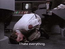 a man is kneeling on the floor with the words i hate everything behind him