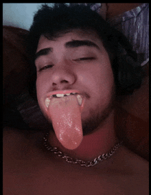 a man with a chain around his neck has his tongue hanging out