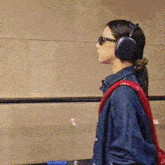 a woman wearing headphones and sunglasses has a backpack