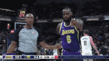 a basketball player wearing a lakers jersey is standing next to a referee