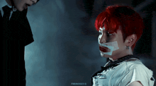a man with red hair is tied to a rope and has a bandage around his mouth