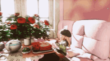 a girl is sitting on a pink couch with a tray of food on it