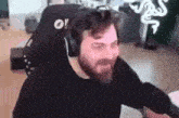 a man with a beard is sitting in a chair wearing headphones and a black shirt .