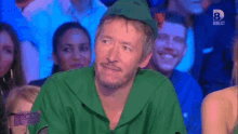 a man in a green costume is sitting in a crowd with a sign that says direct 8