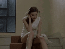 a woman in a white dress is brushing her hair