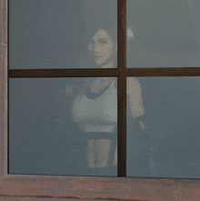 a woman in a sports bra is peeking out of a window
