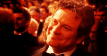 a man in a tuxedo and bow tie smiles in front of a crowd
