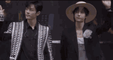 two men are standing next to each other wearing hats and jackets .