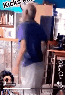 a man in a blue shirt is dancing in a room with a sign that says kicks .