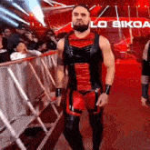 a man in a red and black outfit is walking in a ring with a sign that says losiko on it
