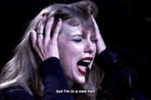 taylor swift is holding her head while singing into a microphone and screaming .