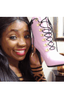 a woman holds up a pair of pink lace up shoes
