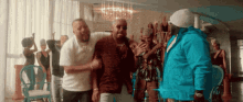 a man in a blue jacket is standing next to two other men in a room