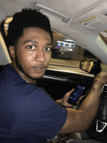 a man is sitting in a car looking at a phone