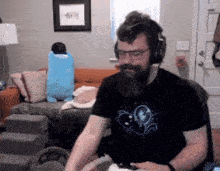 a man with a beard wearing headphones is playing a video game in a living room