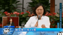 a woman is holding a piece of paper in front of a microphone with the number 44 written on it