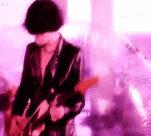 a man in a suit is playing a guitar on a stage in a purple room .