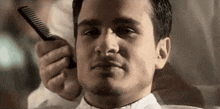 a man is getting his hair cut by a barber and combs his hair .