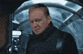 a man in a black jacket is looking at the camera with a serious look on his face