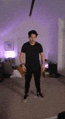 a man in a black t-shirt and black pants is standing in a living room