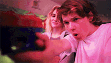 a boy and a girl are playing a video game together and the boy is pointing at something .