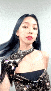 a woman with blue hair is wearing a black sequined dress and earrings .