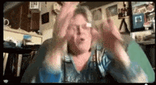 a woman is sitting on a couch making a funny face with her hands .