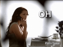 a woman sitting at a table talking on a cell phone with the words oh written above her
