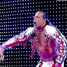 a wrestler in a white and red outfit is standing in front of a screen that says ' n ' on it