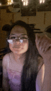 a woman wearing glasses and a pink top is looking at the camera
