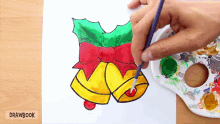 a person is painting a christmas bell with holly